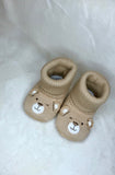 Beige knitted baby booties with bear face design on front of boot. 